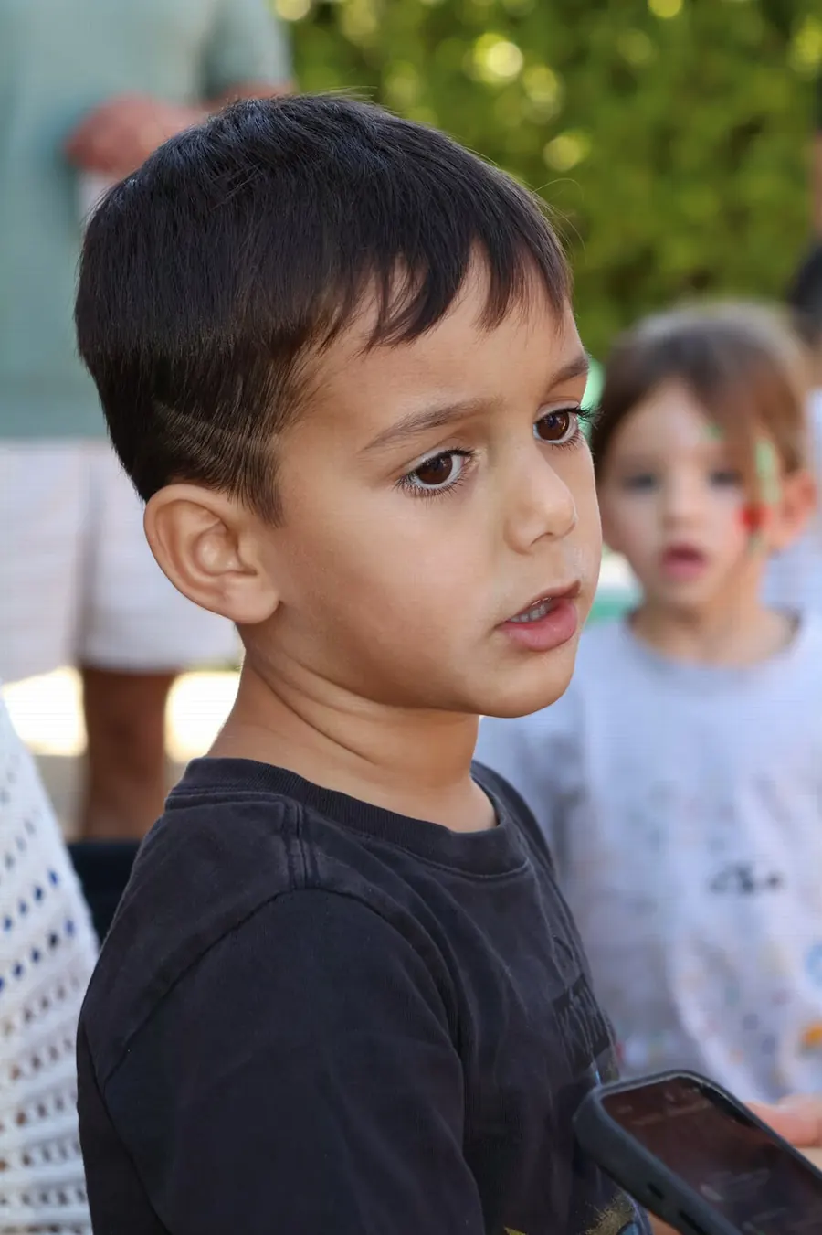 Close candid portrait of a young boy in a black t-shirt looking off camera, photographed by Lihi Matzri